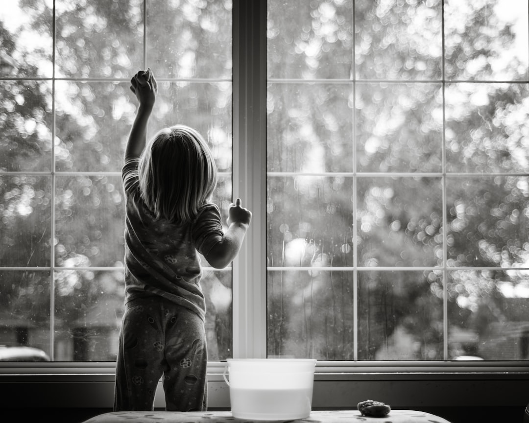 grayscale-photo-of-girl-in-stripe-shirt-and-pants-standing-by-the-window-fcszfjeb87k